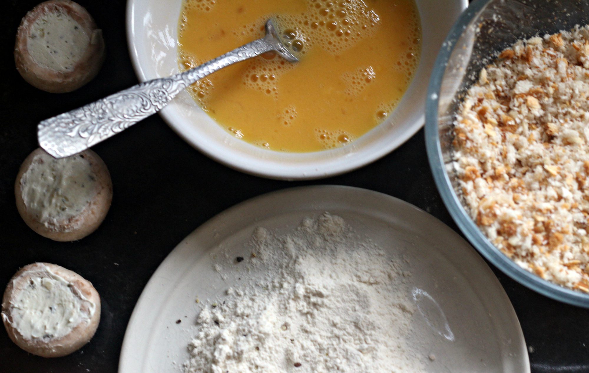 Beaten egg with seasoned flour and breadcrumbs ready to make Garlic Mushrooms